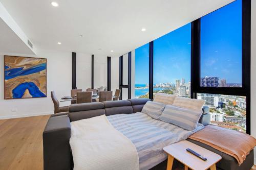 a living room with a couch and large windows at Skyline Showdown - Views, Games & Vibes in Gold Coast
