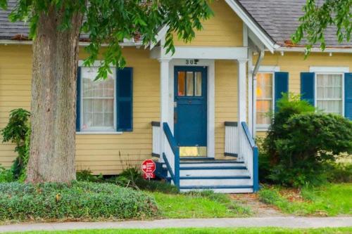 a yellow house with a blue door and a tree at Big Comfy Home with King & Queen Beds in Lafayette