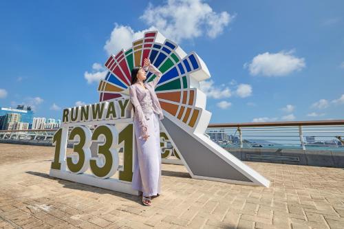 香港にあるRunway 1331 - Enlightの看板の前に女性が立っている