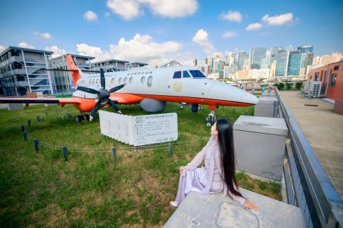 香港にあるRunway 1331 - Enlightの棚に座って飛行機を眺めている女の子