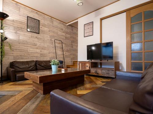 a living room with a couch and a tv at Kokoro house in Osaka
