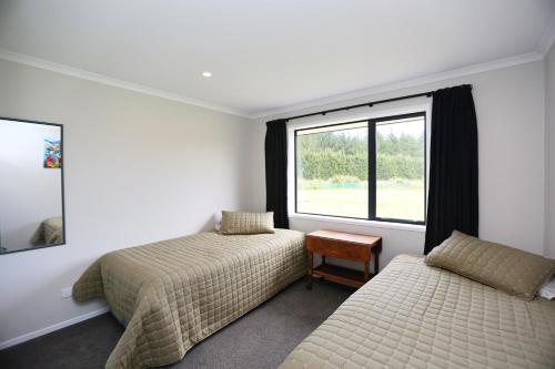 een slaapkamer met twee bedden en een raam bij Forest Charm by the Beach in Waitarere