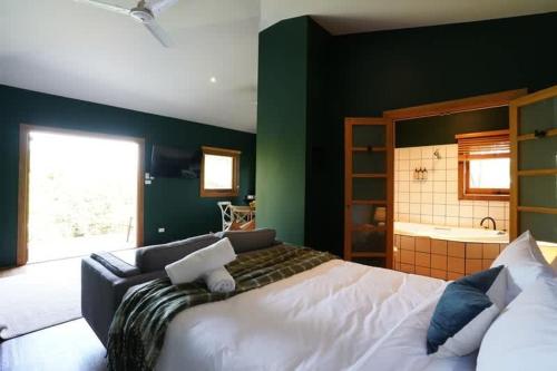 a bedroom with a white bed and a green wall at Central studio with spabath in Daylesford