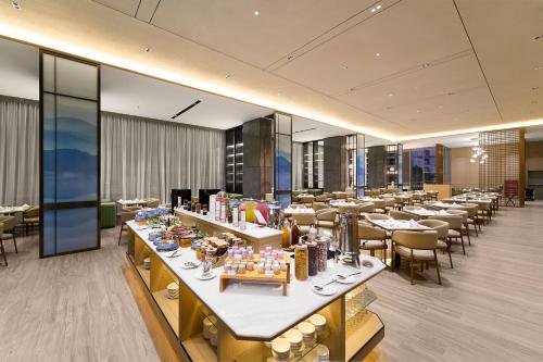 ナゴヤにあるHARRIS Hotel & Suites Nagoya Batamの部屋にテーブルと椅子があるレストラン