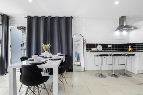 a kitchen with a white table and black chairs at The Coastal Escape - Games & Vibes in Gold Coast