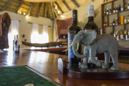 a figurine of an elephant standing next to wine bottles at Gondwana Hakusembe River Lodge in Rundu