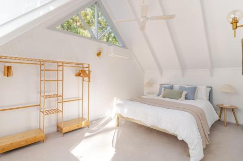 ein weißes Schlafzimmer mit einem Bett und einem Fenster in der Unterkunft Cosy 2 Bedroom Cottage with spabath and fireplace in Mount Dandenong