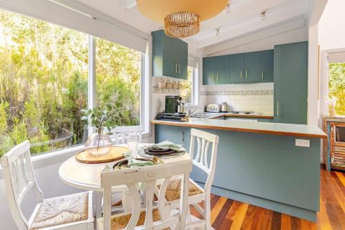 a kitchen with green cabinets and a table and chairs at Cosy 2 Bedroom Cottage with spabath and fireplace in Kalorama
