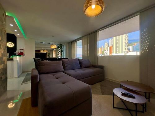 a living room with a brown couch and a large window at Apartamento moderno en cabecera Bucaramanga in Bucaramanga