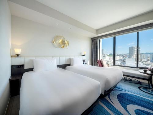 two beds in a hotel room with a large window at Hyatt Regency Naha, Okinawa in Naha