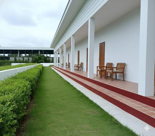 an empty porch of a white building with grass at Vapanakhaw Ubon in Ubon Ratchathani