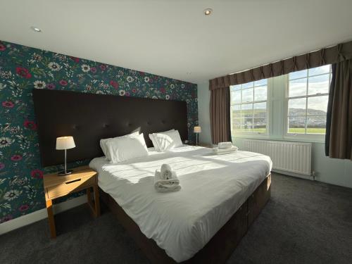 um quarto com uma cama grande com lençóis brancos e uma mesa em The Portpatrick Hotel by Compass Hospitality em Portpatrick
