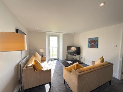 a living room with two couches and a tv at The Portpatrick Hotel by Compass Hospitality in Portpatrick