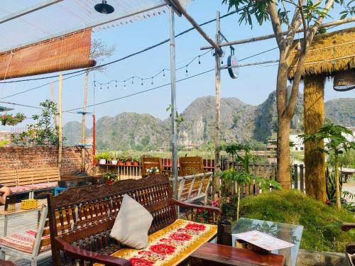 eine Bank auf einer Terrasse mit Bergen im Hintergrund in der Unterkunft Tam Coc Mango hostel in Vũ Lâm