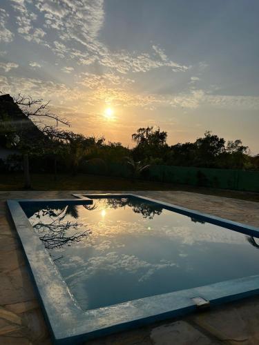 ein Wasserbecken mit dem Sonnenuntergang im Hintergrund in der Unterkunft Msafiri House in Kizimkazi