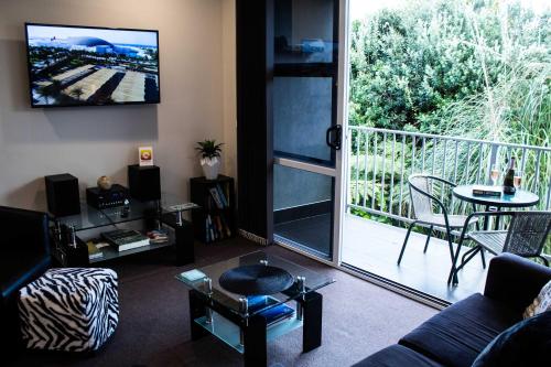 a living room with a couch and a tv and a balcony at The Strandon - loft style central apartment in New Plymouth