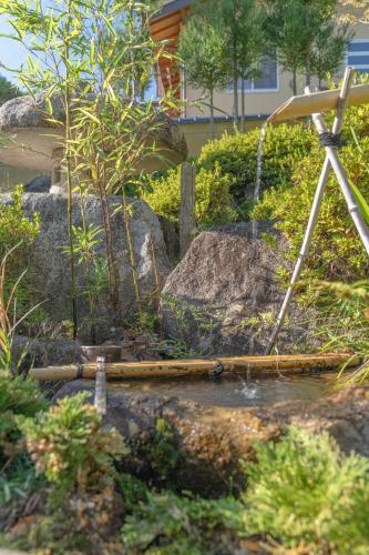 a garden with a water fountain and a tripod at BANRYU 萬龍 バンリュウ in Iida