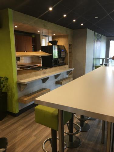 a room with tables and a kitchen with a counter at ibis budget Metz Technopole in Metz