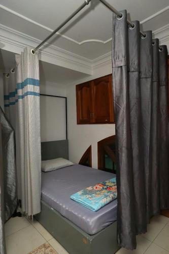 a small bed in a room with a curtain at Sakurahad Sai Gon Hostel in Kon Rung (1)