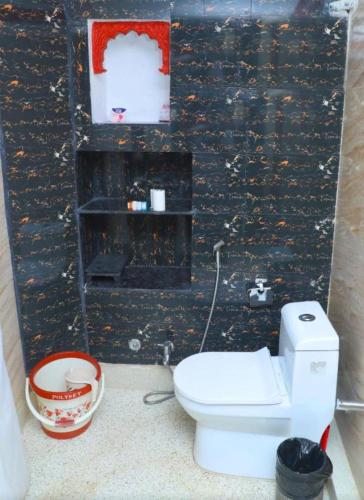 a bathroom with a white toilet and a black wall at The Rajputana Heritage in Jodhpur