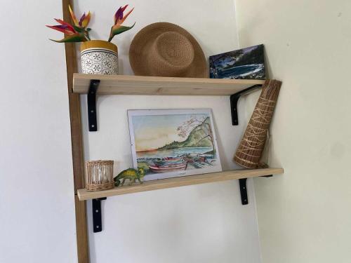 una mensola di legno su una parete con un quadro e dei cappelli di La kazolie a Sainte-Rose