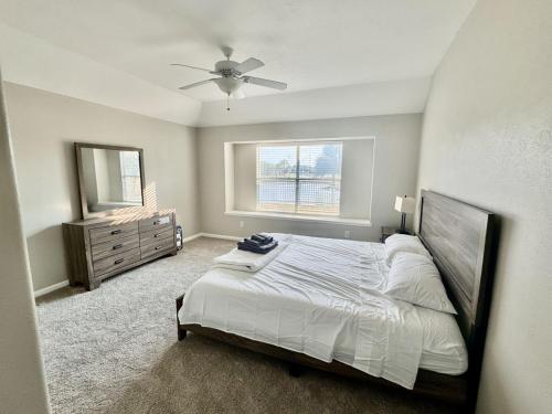 a bedroom with a bed with a ceiling fan and a dresser at Katy Getaway - Relaxed 3BR Home with Serene Views in Hoffpauir Airport