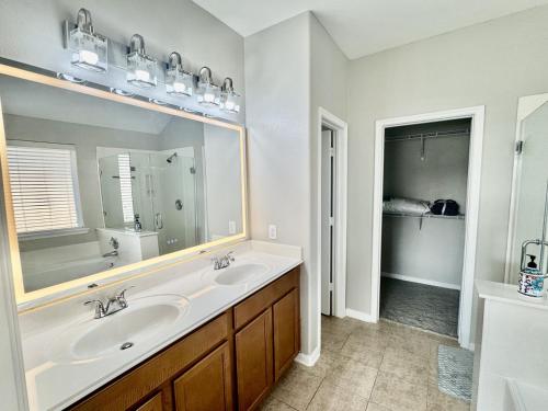 a bathroom with a sink and a large mirror at Katy Getaway - Relaxed 3BR Home with Serene Views in Hoffpauir Airport