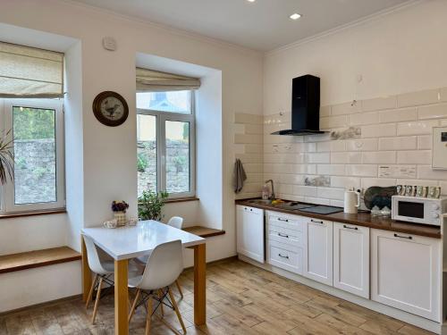 a kitchen with white cabinets and a table with chairs at Апартаменти біля Фортеці in Kamianets-Podilskyi