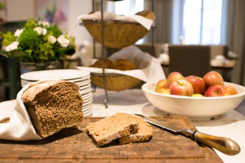 a cutting board with a loaf of bread and a bowl of apples at Boardinghouse Hotel Münchner Hof Pfarrkirchen in Pfarrkirchen