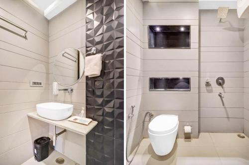 Un baño con inodoro, lavabo y espejo. en Hotel Golden Prime Delhi International Airport, en Nueva Delhi