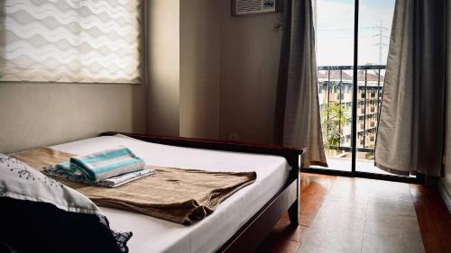 een slaapkamer met een bed en een raam met uitzicht bij Spacious Central Davao City Getaway - Spacious Apartment with Shared Pool in Cabaguio