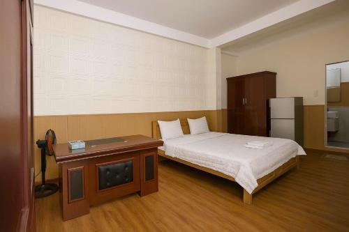 a bedroom with a bed and a table and a refrigerator at Khách Sạn Anh Anh in Ho Chi Minh City