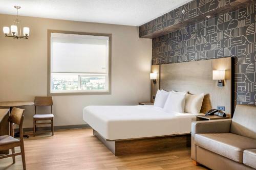 a hotel room with a bed and a couch at Days Inn & Suites by Wyndham West Edmonton in Edmonton