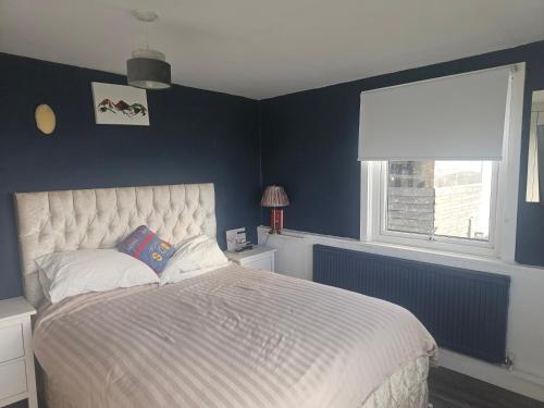 a bedroom with a bed with blue walls and a window at Sandylands in Braystones