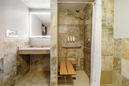 a bathroom with a shower with a bench next to a sink at AmericInn by Wyndham Chamberlain Conference Center in Chamberlain