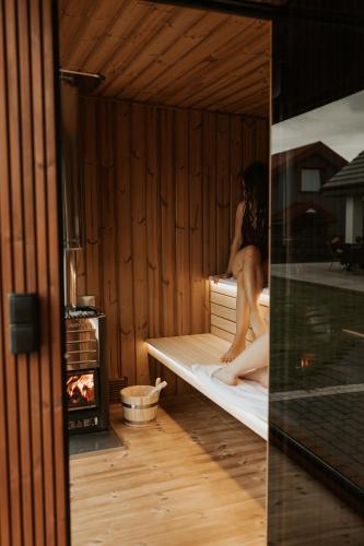 a woman sitting on a bed in a sauna at Dom Marina Mosty, Sauna Hot Tub Holiday Home near Rewa Gdańsk in Mosty