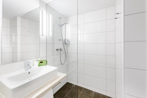 uma casa de banho branca com um lavatório e um chuveiro em ibis budget Konstanz em Constança