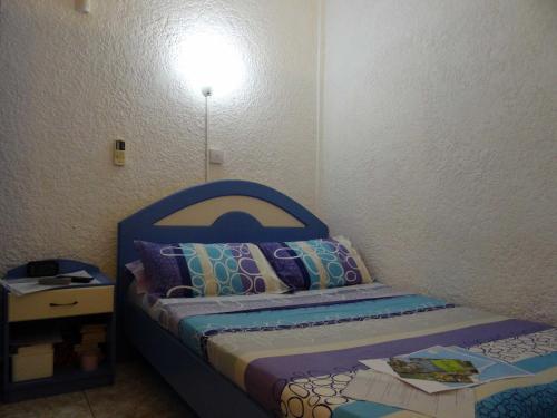 una piccola camera con letto con testiera blu di Cool Studio a Flic-en-Flac