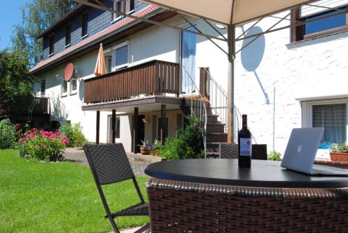 ein Tisch mit einer Flasche Wein und ein Laptop darauf in der Unterkunft Ferienwohnung Gartenstrasse in Gersfeld
