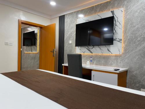 a hotel room with a desk and a tv on the wall at Chateux de atlantique Hotel in Lagos