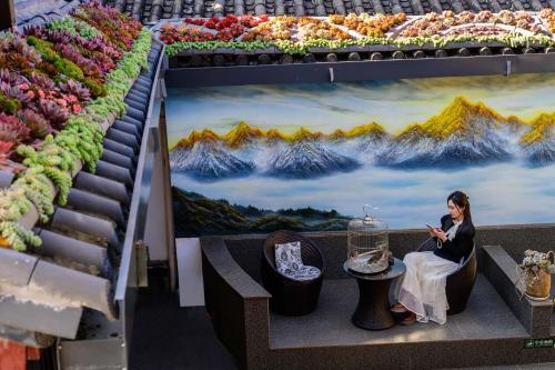 麗江市にあるGolden Dragon's Mountain Glow Innの花が飾られた店内のベンチに座っている女性