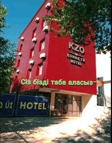 a red hotel with a hotel sign in front of it at КзО in Shymkent