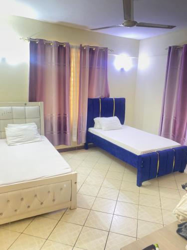 two beds in a room with purple curtains at Amore Cosy 2 Bedroom Apartment in Mombasa