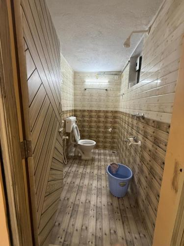 a bathroom with a toilet and a blue bucket at GYANi 1 in Tiruvannāmalai