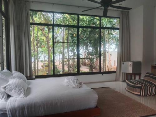 a bedroom with a large window and a white bed at Villa89 Chumphon 