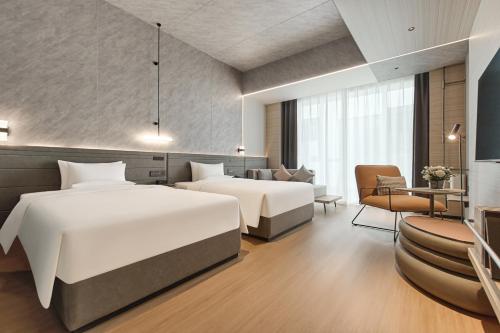 銀川市にあるNovotel Yinchuan Lanxiguのベッド2台とソファがあるホテルの部屋