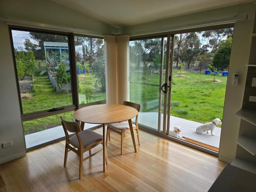 a dining room with a table and a dog looking out the window at Urban Retreat near Hobart & Airport, Port Arthur in Penna
