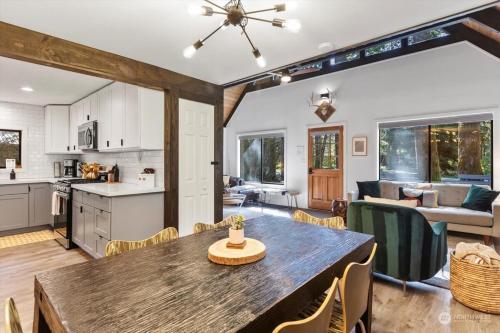 a kitchen and living room with a wooden table and chairs at Luxury A-Frame with Hot Tub, Fireplace & Firepit in Skykomish