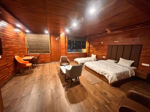 パランプールにあるHotel Postcardのベッド2台とテーブルと椅子のある寝室