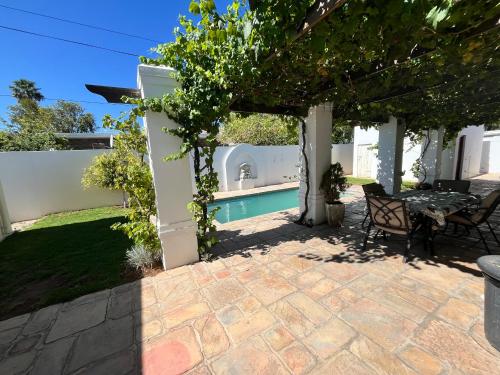 a patio with a table and chairs under a pergola at Toni's Cottage in Graaff-Reinet